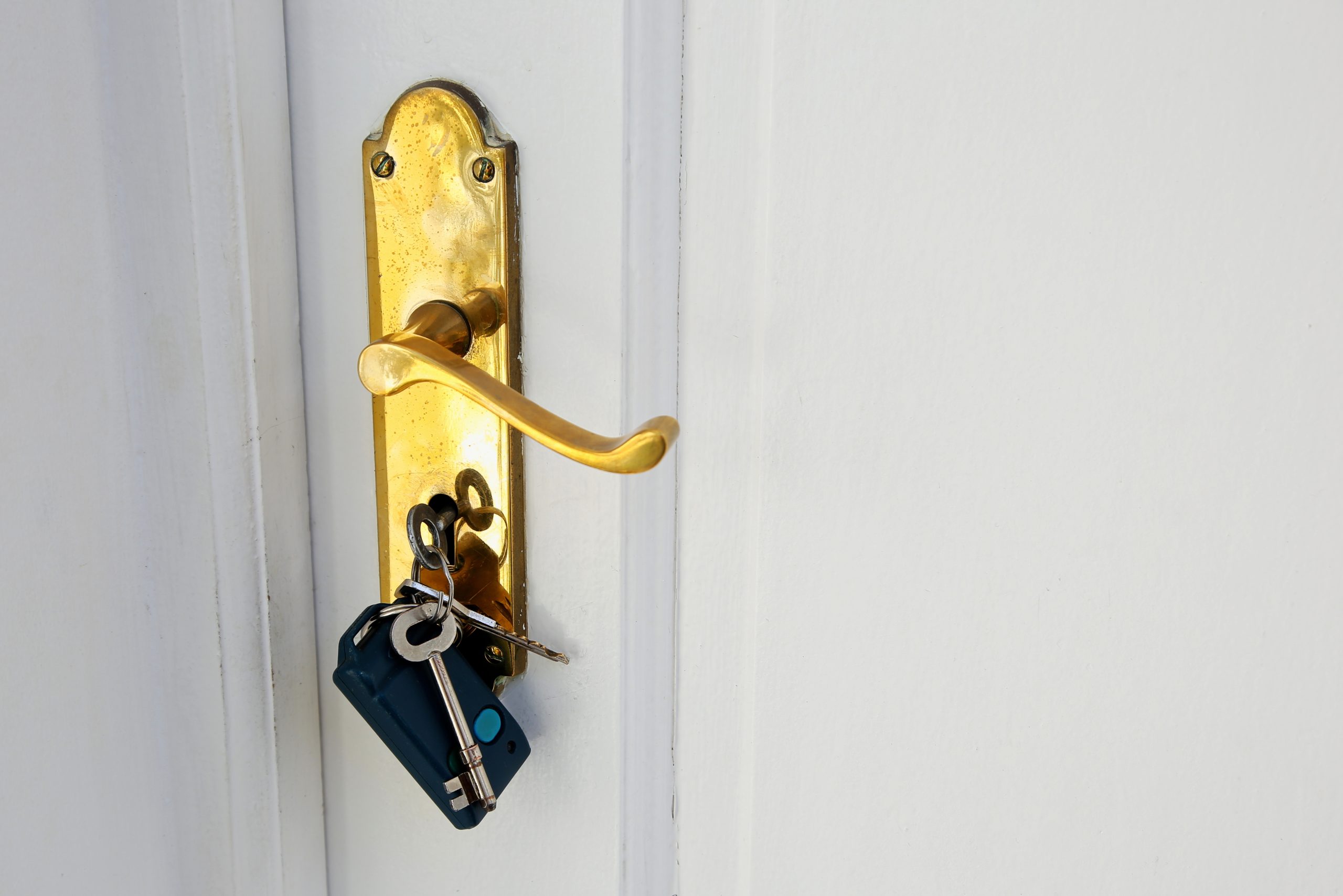 A golden doorknob with keys on a white door